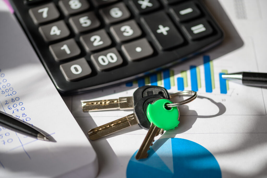 Close-up of a calculator, car keys, and financial documents with graphs and notes